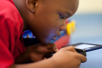 Akintunde Udo, 6, is engrossed in a game at a UCI Health center for patients with autism.